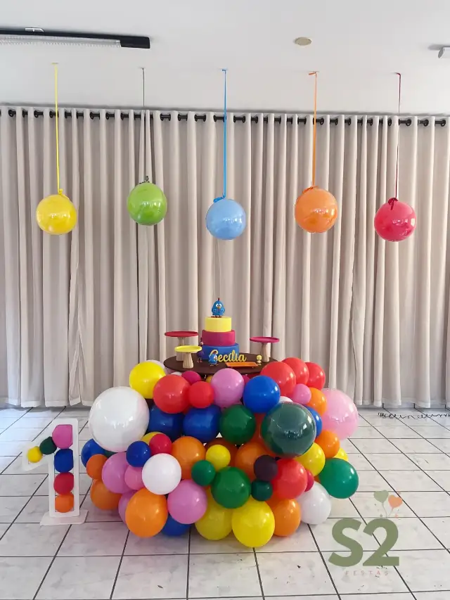 Decoração colorida moderna, com balões de várias cores em volta da mesa e balões pendurados